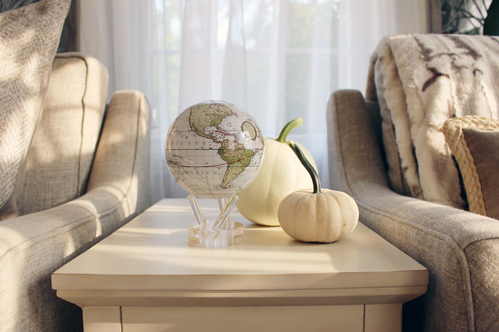 Antique terrestrial white mova globe surrounded by fall decor